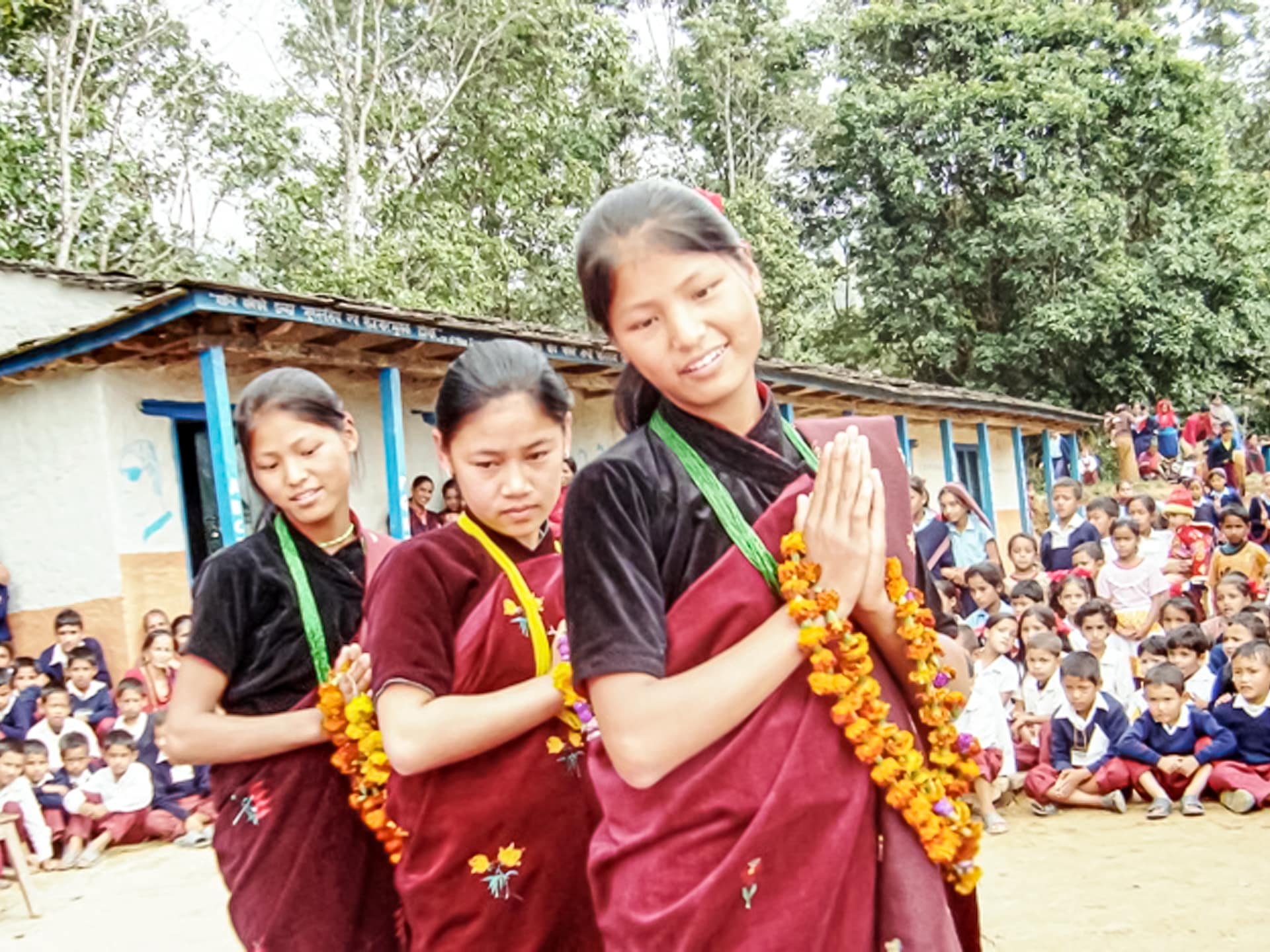 Schulkinder sitzen zu einer Feierlichkeit des Nepalschulprojektes auf dem Schulhof.